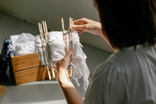Back view of crop anonymous female artisan wrapping cotton textile around poles with threads while demonstrating tie dye technique
