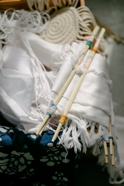 High angle of poles with threads on folded textiles with fringes for tie dye in sunlight