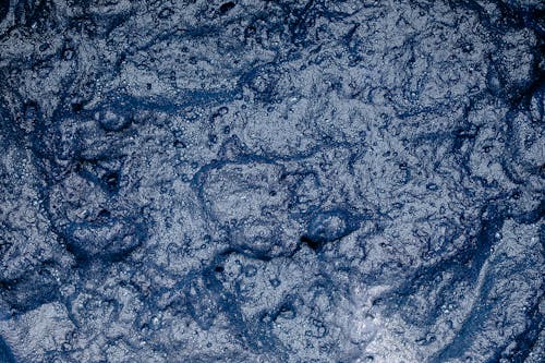 From above of surface of foamy indigo colored water during shibori tie dyeing process as abstract background