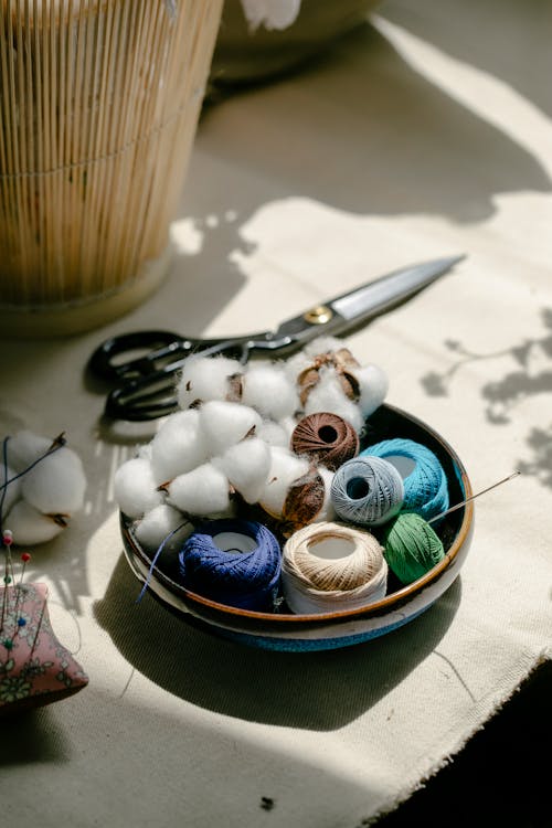 Free Thread bobbins with scissors and needles placed on table in atelier Stock Photo