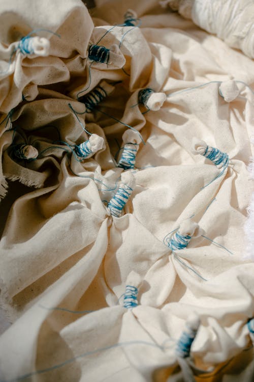 From above of crumpled light fabric tied with threads in shibori technique in daytime