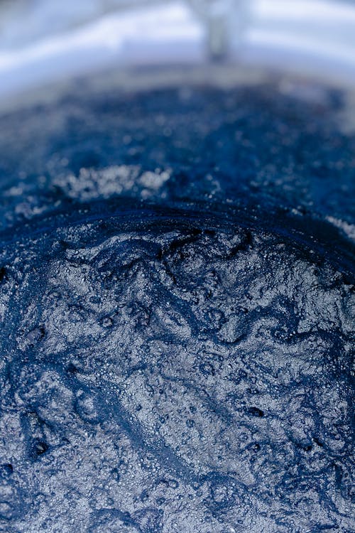 Closeup of vessel filled with blue water with drops and ripple on surface