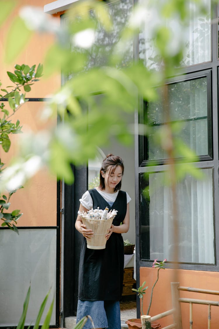 Young Woman With Basket Going Out Of Opened Door