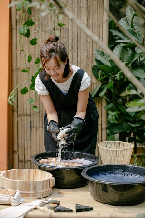 Smiling ethnic artisan squeezing cloth while showing shibori technique