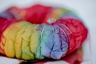 Closeup of folded cloth with multicolored paints tied with threads representing traditional Japanese tie dye technique