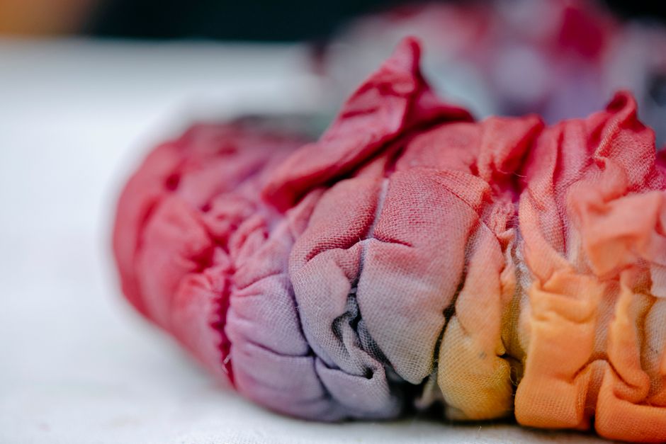 Focused shot of colorful, creased tie-dye fabric, showcasing its vibrant spectrum and texture.