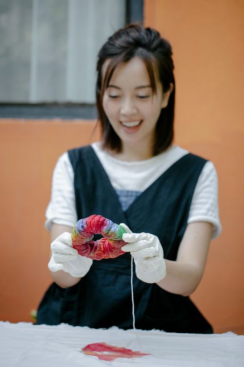 Free Smiling woman in gloves creating colorful tie-dye fabric indoors. Stock Photo