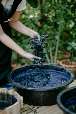 Hands lifting dyed clothespins from an indigo vat — Photo by Teona Swift on Pexels