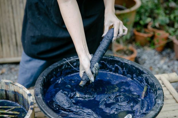 Hands dipping cloth into an indigo dye vat — photo by Teona Swift on Pexels