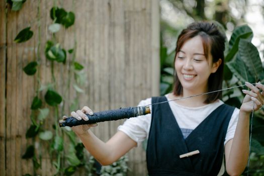 Smiling young woman enjoying her shibori dye crafting in a garden setting, showcasing creativity and traditional techniques.
