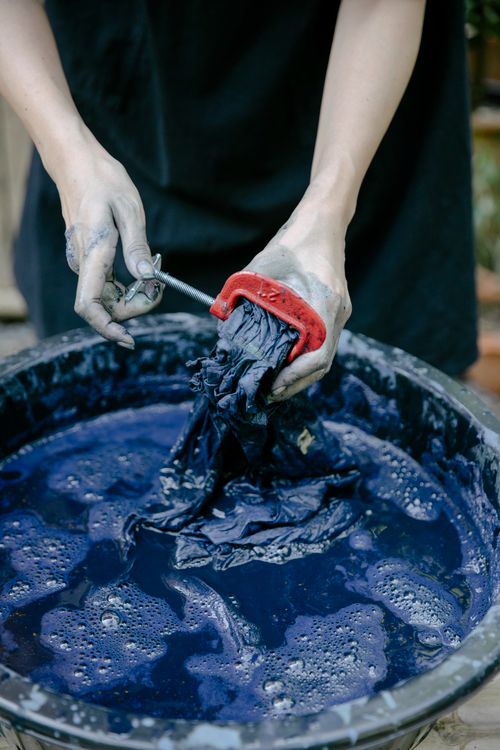 Free Close-up of hands dyeing fabric in a blue tie-dye process using a large basin. Stock Photo
