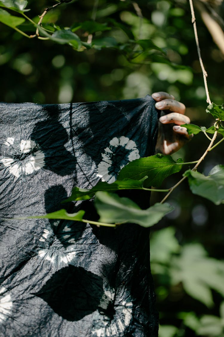 Stained Hand Holding Up Tie Dyed Fabric