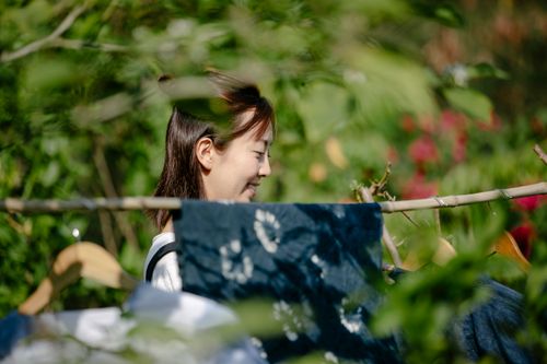Free A young woman enjoying outdoor tie-dye crafting amidst lush greenery. Stock Photo