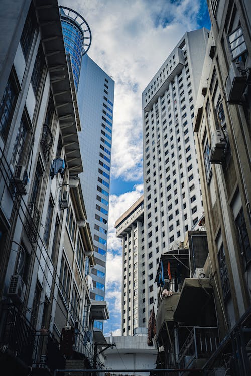 Low angle of contemporary multistory buildings with creative design and residential houses located on narrow street in modern district of city