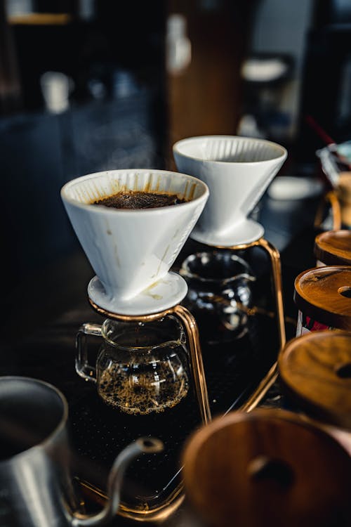 Kettles with drippers and filters for brewing pour over coffee placed on table with professional equipment in coffee shop on blurred background