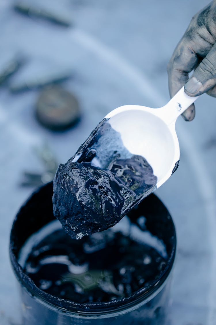 Hand With Spatula Taking Mud From Bottle