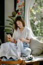 Smiling Asian woman sewing fabric in workshop