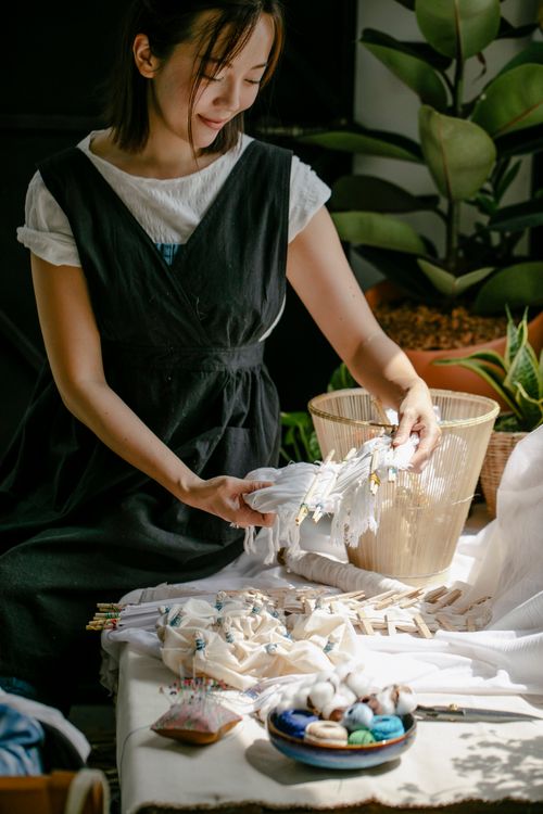 Free Crop positive female designer preparing fabric on knitting needles for dying with Japanese manual shiboru technique Stock Photo