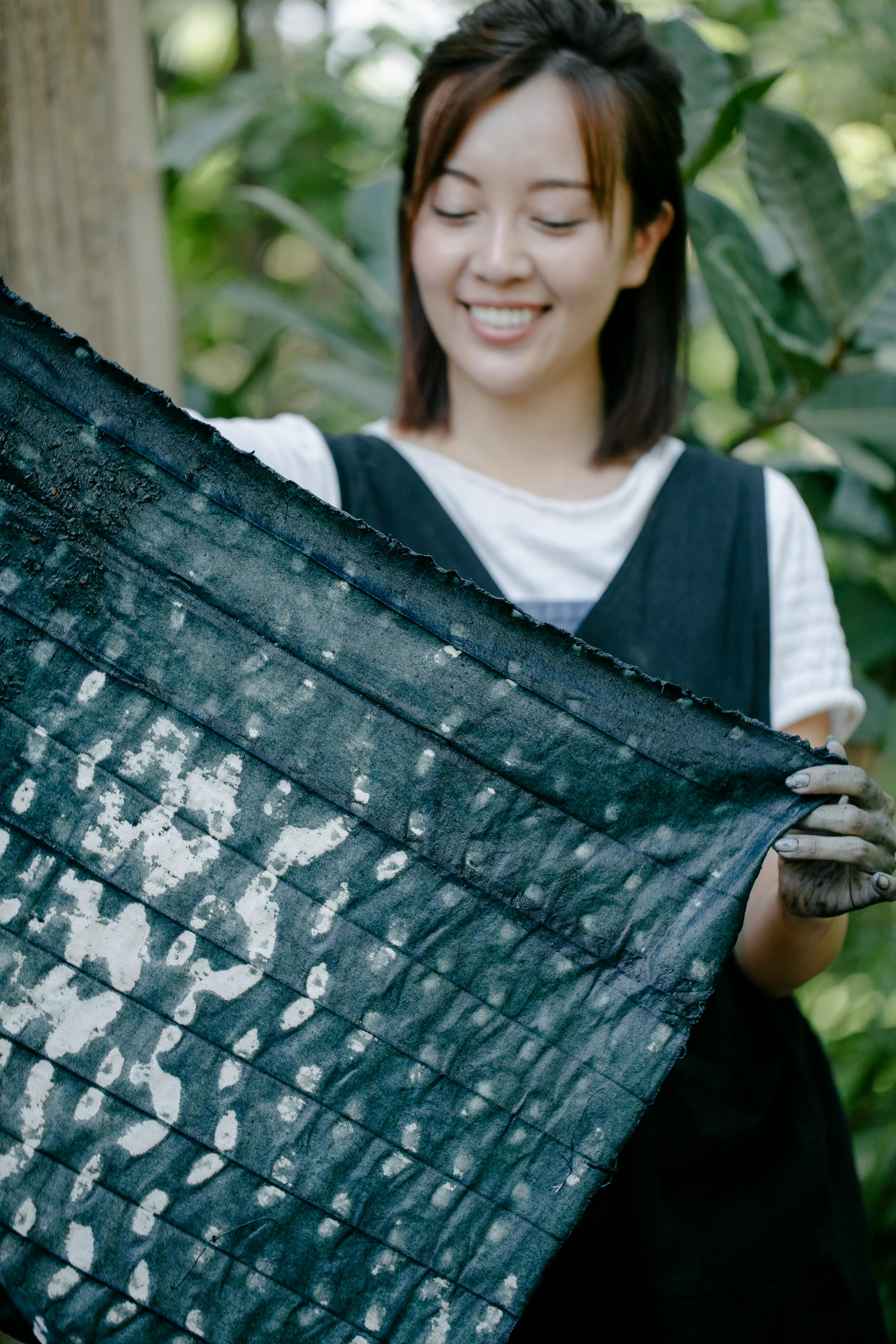 cheerful asian woman with painted cloth in hands