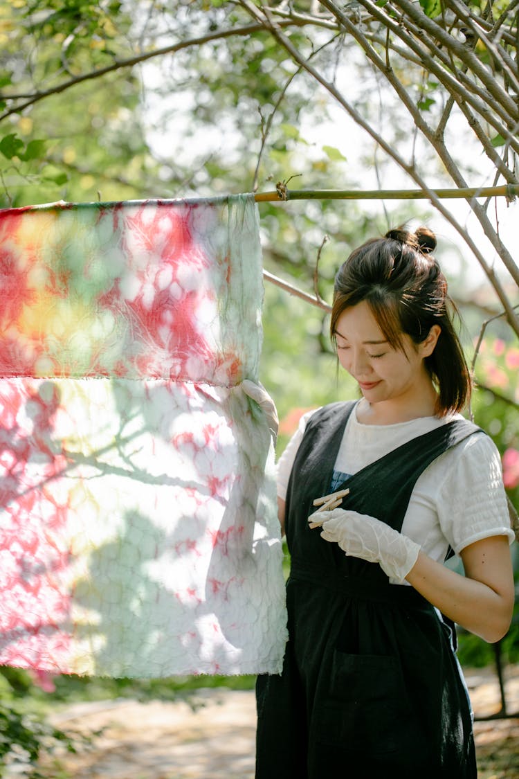 Content Asian Woman Near Painted Cloth In Countryside