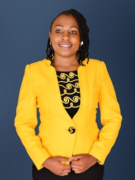 Portrait of a confident African American woman wearing a yellow blazer. Studio shoot with a neutral background.