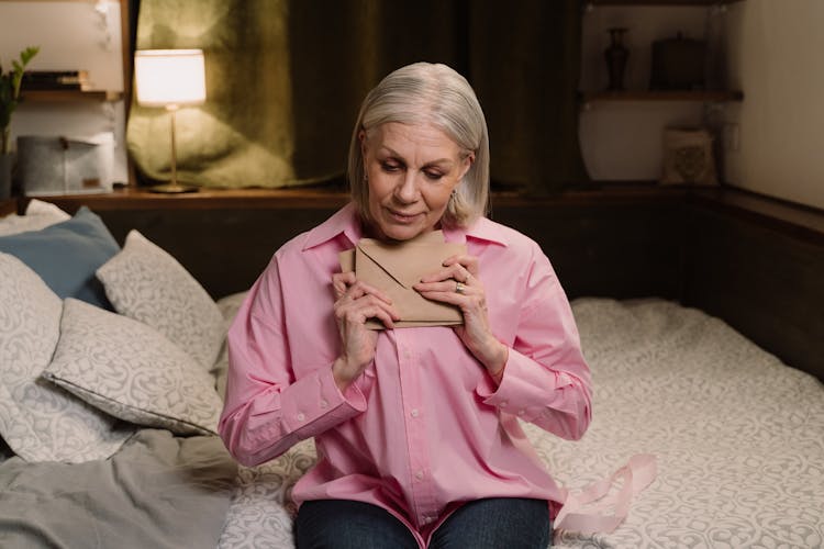 Woman In Pink Long Sleeve Shirt Holding Brown Envelopes