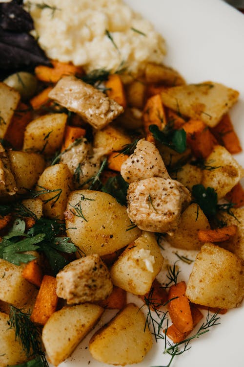 Delicious dish with fried potatoes and carrots served with herbs