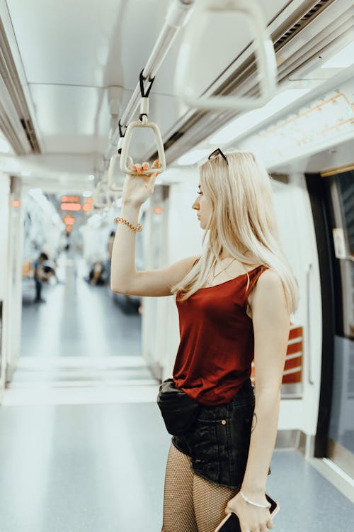 Young woman holding handrail while commuting by contemporary train