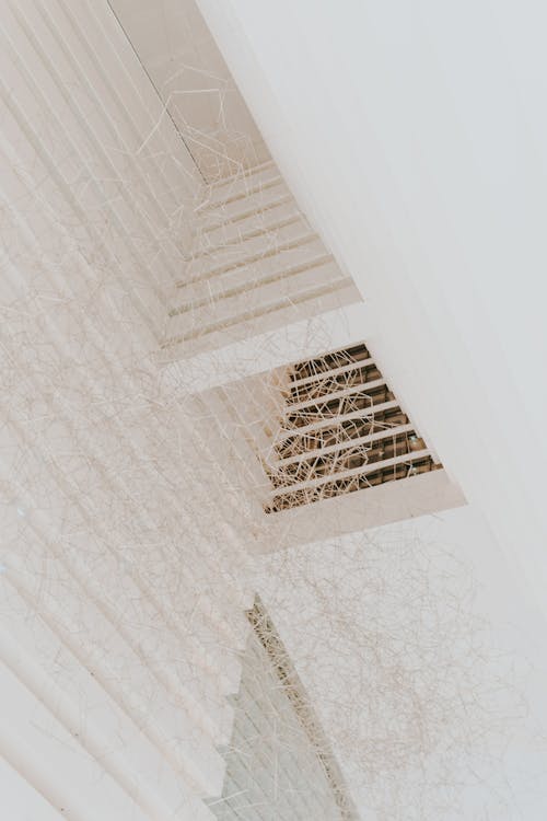 From below of minimalist geometric ceiling with creative thin wire chandelier in daylight