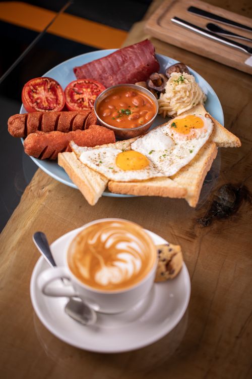 Free Enjoy a classic full English breakfast with eggs, sausage, beans, and cappuccino, perfect for a hearty start. Stock Photo