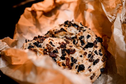 Close-up of freshly baked olive bread on brown paper, perfect for food lovers.