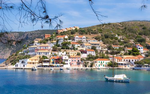 Free Vibrant houses overlook a serene bay in Assos, Greece, a picturesque coastal village. Stock Photo