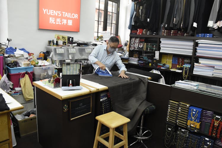 Man Wearing A Face Mask Ironing The Fabric 