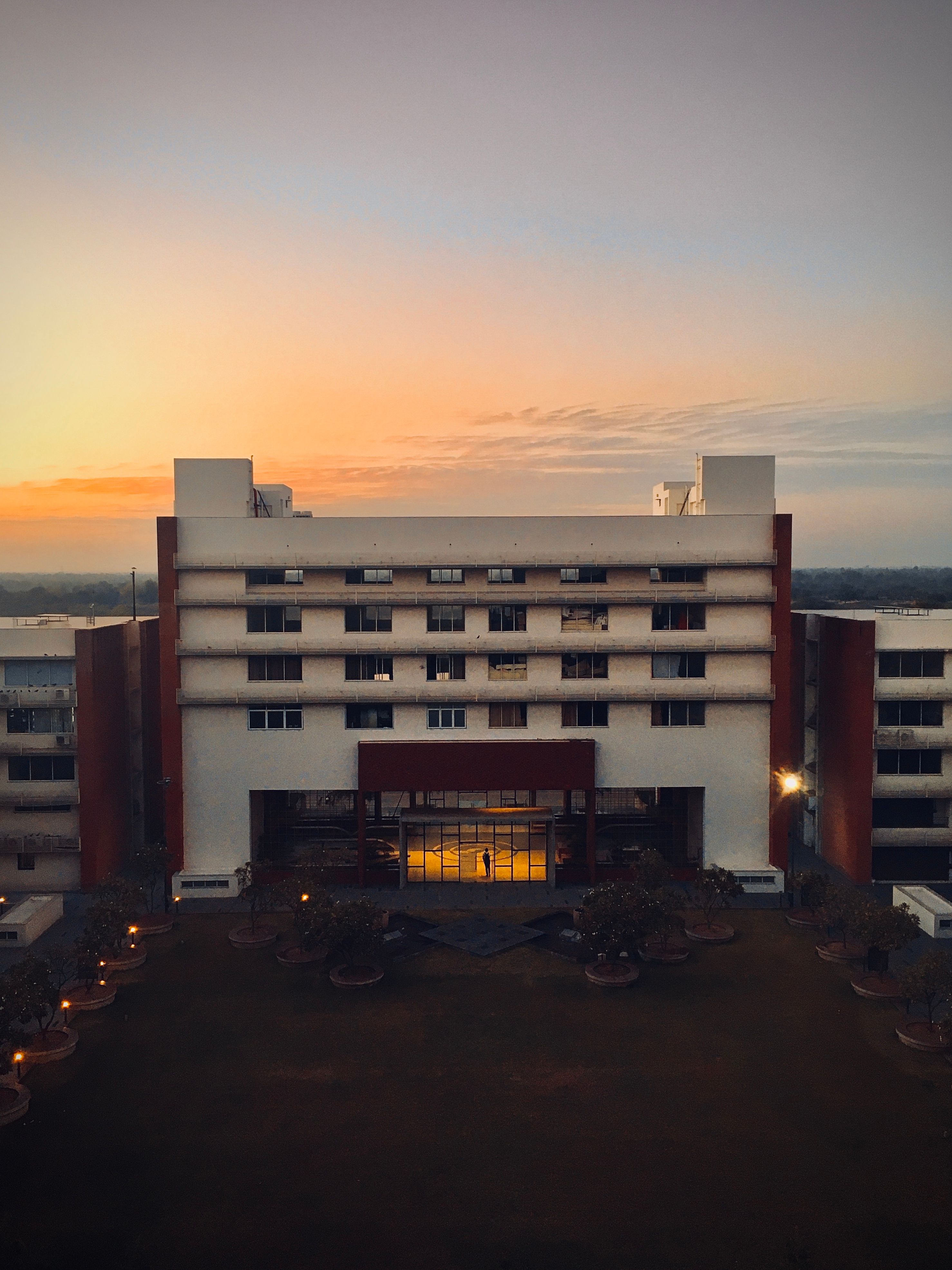 A modern architectural building captured at sunset with glowing glass windows.