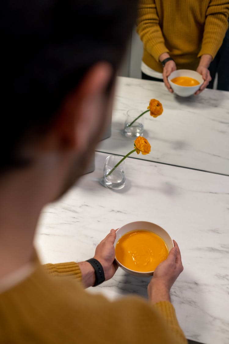 A Person Holding A Bowl Of Pumpkin Soup