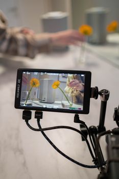 Camera monitor displays close-up of flowers during indoor video shoot.