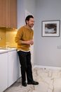 Man in Yellow Sweater Standing Near White Wall