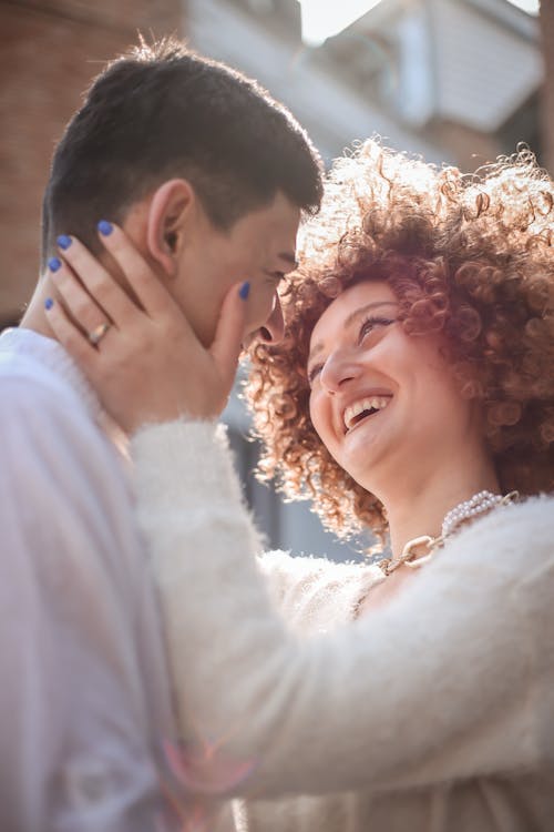 Happy Woman with Curly Hair Touching a Man's Face