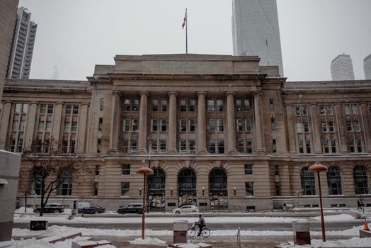 Facade of famous office building with flag located on street near modern skyscrapers on cold winter day in Toronto city