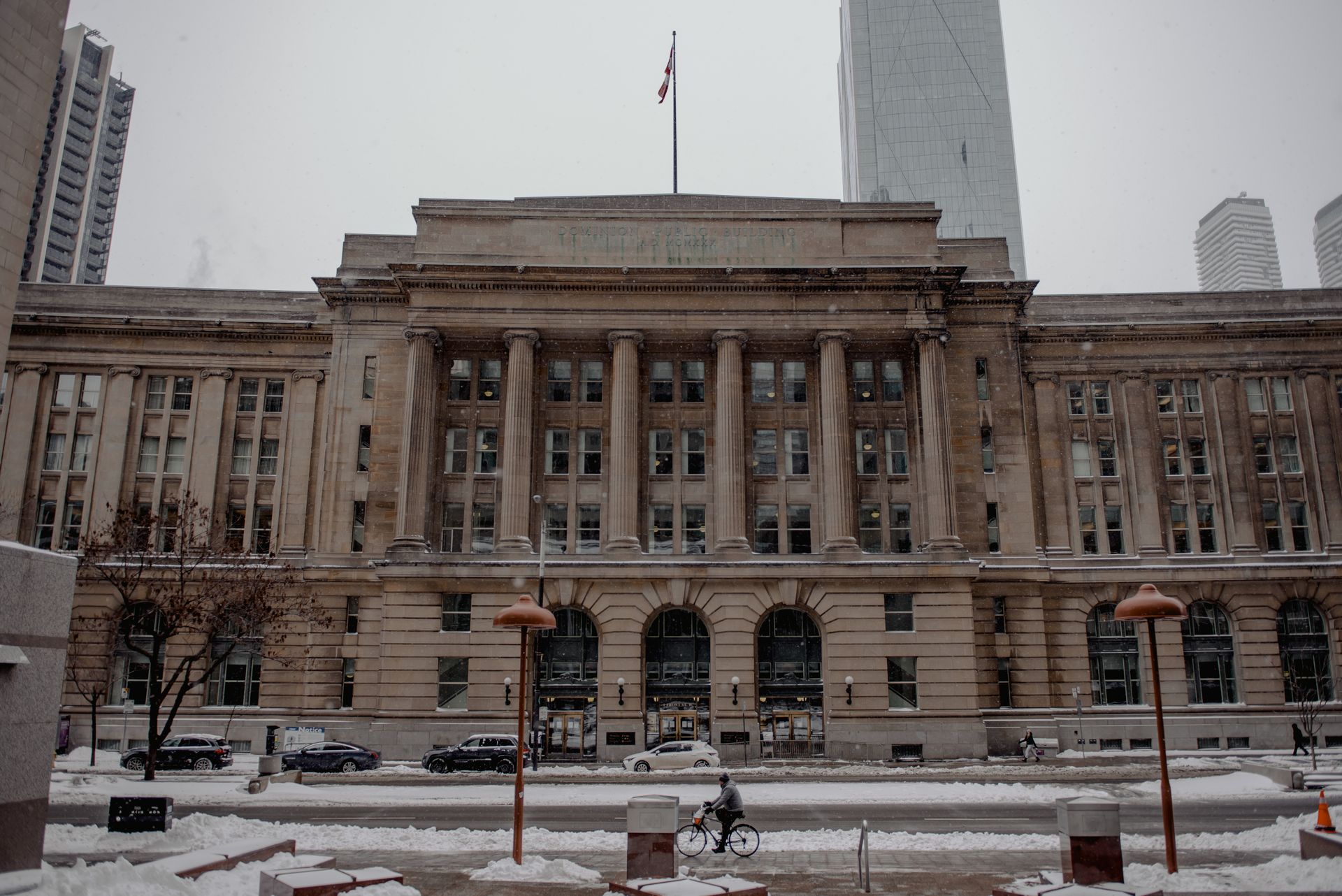 Facade of famous office building with flag located on street near modern skyscrapers on cold winter day in Toronto city