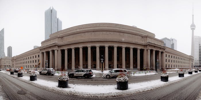 Panoramic winter view of Toronto's Union Station with CN Tower in the background.