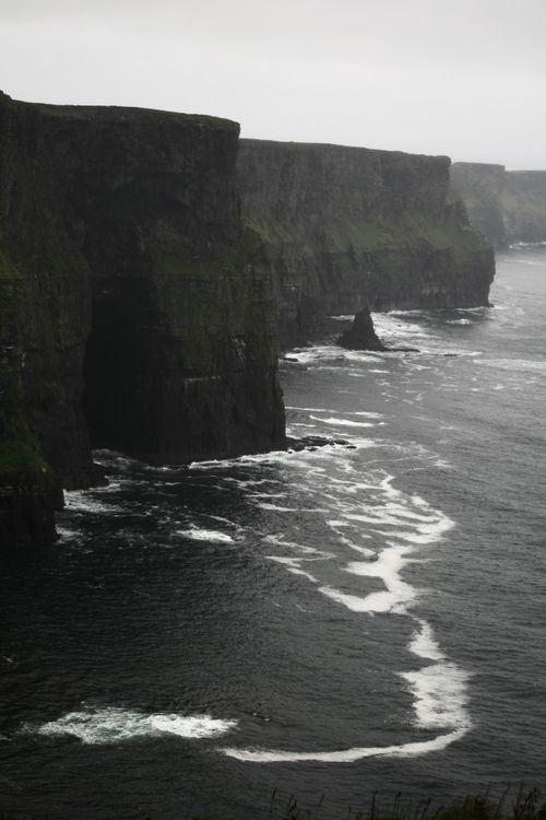 Free A gloomy view of the Cliffs of Moher with the ocean waves crashing below. Stock Photo