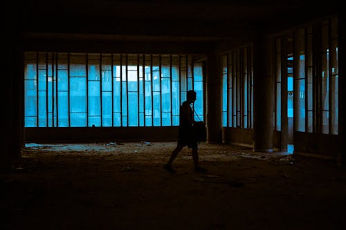 Silhouette of Person Walking Inside a Dark and Abandoned Building