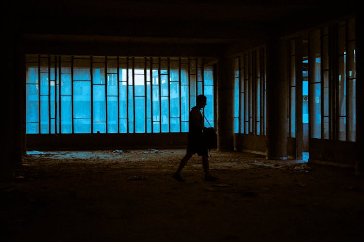 Silhouette Of Person Walking Inside A Dark And Abandoned Building