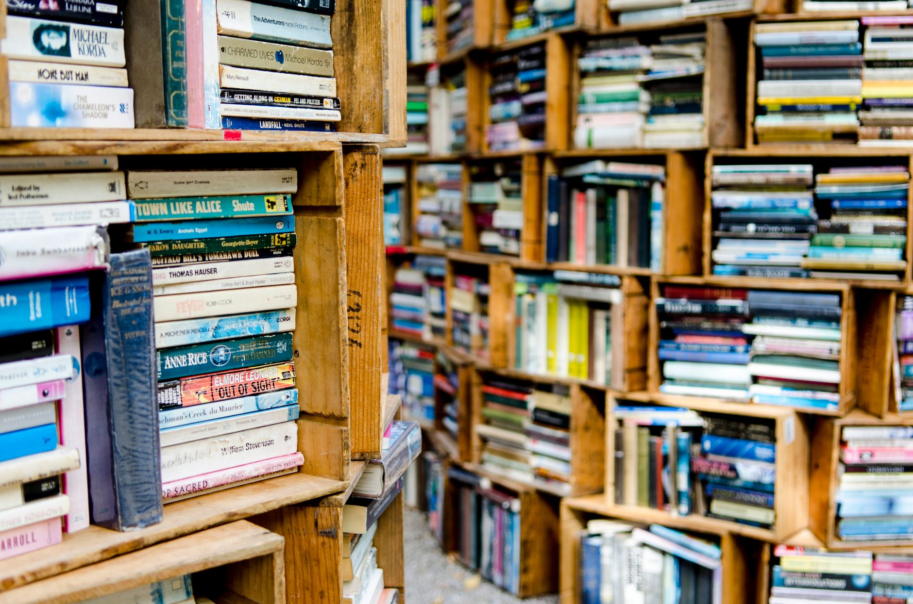 Colorful assortment of books stored in wooden bookshelves of varying sizes.