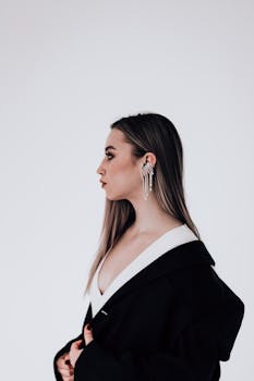 Side view portrait of a fashionable young woman with earrings against a white backdrop.