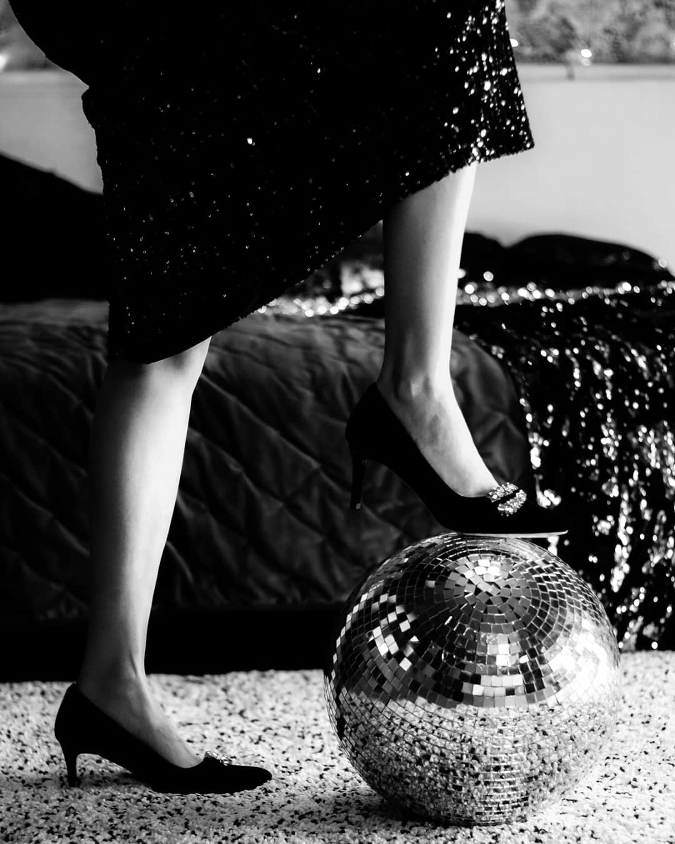 grayscale photo of person stepping on a disco ball