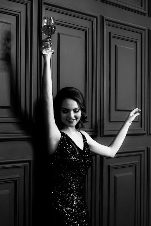 Happy lady in dress with raised hands and wineglass