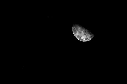 From below third quarter glowing moon shining on dark starless sky at late night