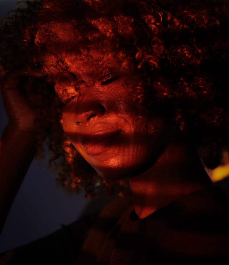 Woman With Curly Hair And Reflection Of Light On Face